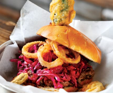 Burger topped with pork, slaw, and a fried jalapeno.