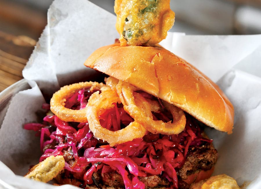 Burger topped with pork, slaw, and a fried jalapeno.