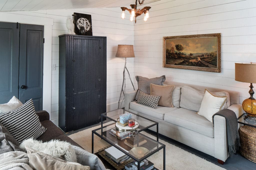 Living room with antique light feature and white wood walls.