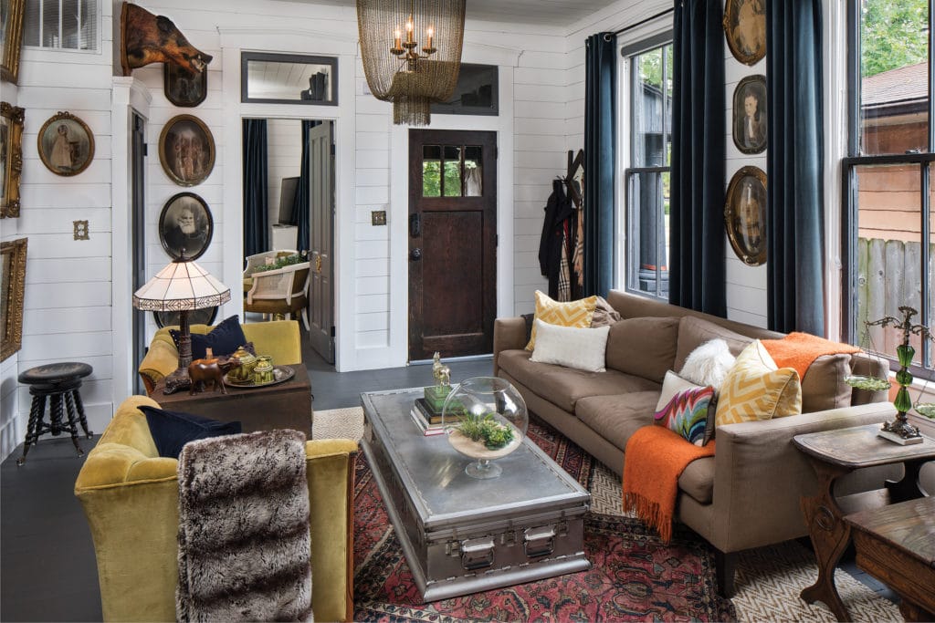 Living room with white wood walls and antique style portraits.