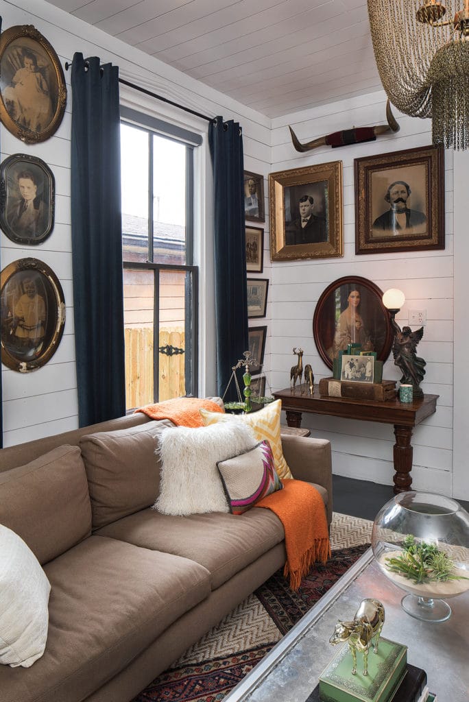 Living room with white wood walls and antique style portraits.