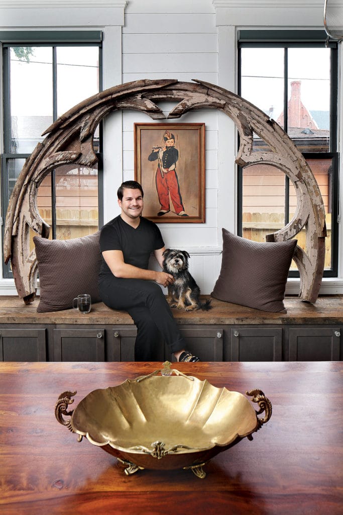 Man posed with dog on kitchen bench.