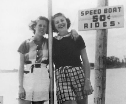 Old photo of two girls by speed boat ride sign