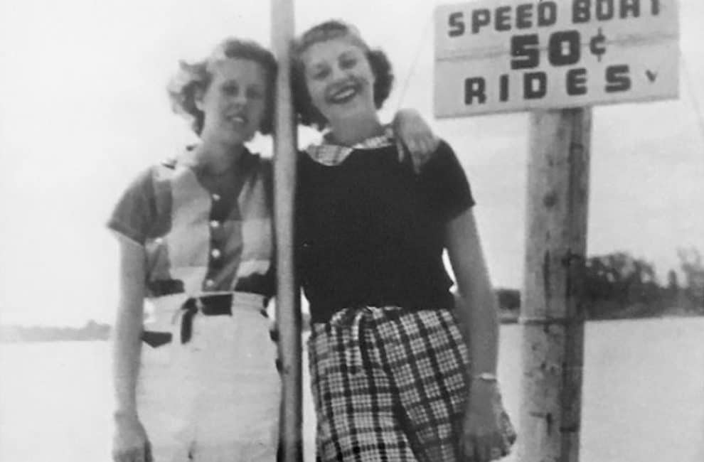 Old photo of two girls by speed boat ride sign