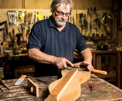 Man, Bill Berg crafts a dulcimer, an hourglass shaped musical instrument.