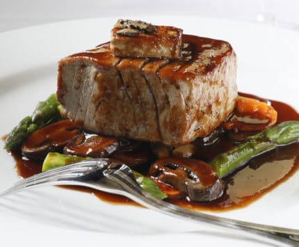 Plated steak with mushrooms and asparagus with sauce at Ocean Prime