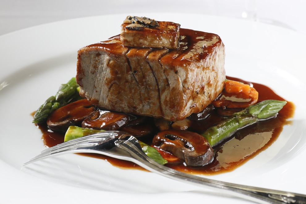 Plated steak with mushrooms and asparagus with sauce at Ocean Prime