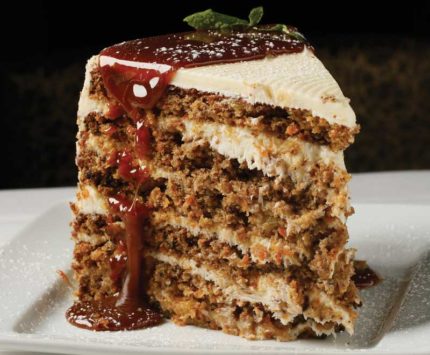 A towering slice of carrot cake covered in a caramel sauce