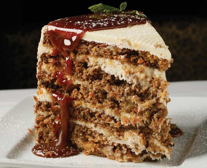 A towering slice of carrot cake covered in a caramel sauce