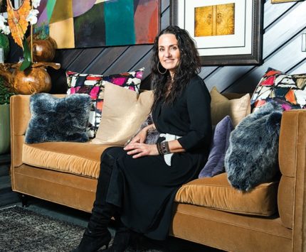 A woman wearing all black sits on a designer couch.