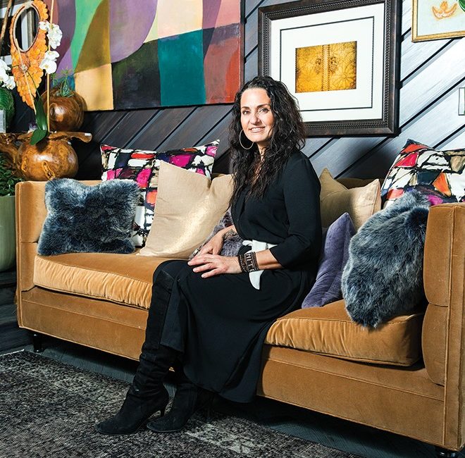 A woman wearing all black sits on a designer couch.