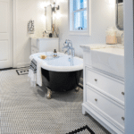 A black and white tiled bathroom with a clawed-foot bathtub.