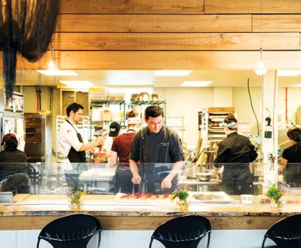 A gentleman wearing an apron works in a busy pastry kitchen.