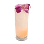 A pink cocktail in a tall high ball glass with an orchid blossom as garnish