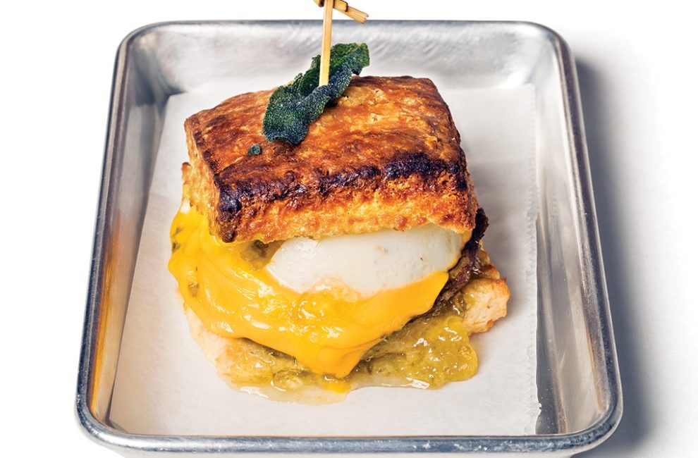 A metal sheet pan lined in parchment holds a biscuit sandwich