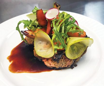 A colorful plate of food that includes roasted carrots, sliced raddish, and pickles.