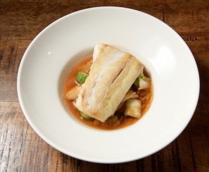 A generous portion of white fish over a light brown transluscent broth of dashi and kimchi