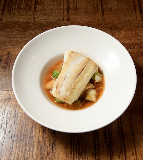 A generous portion of white fish over a light brown transluscent broth of dashi and kimchi