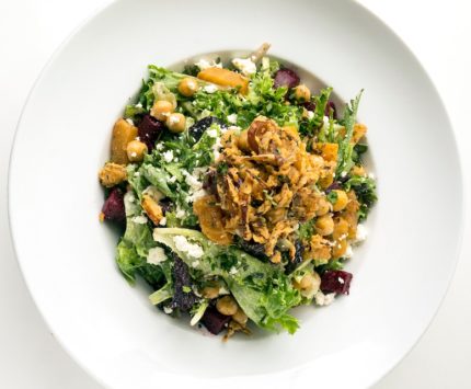 A green salad with fried shallots, red and golden beats, and sheep’s milk feta