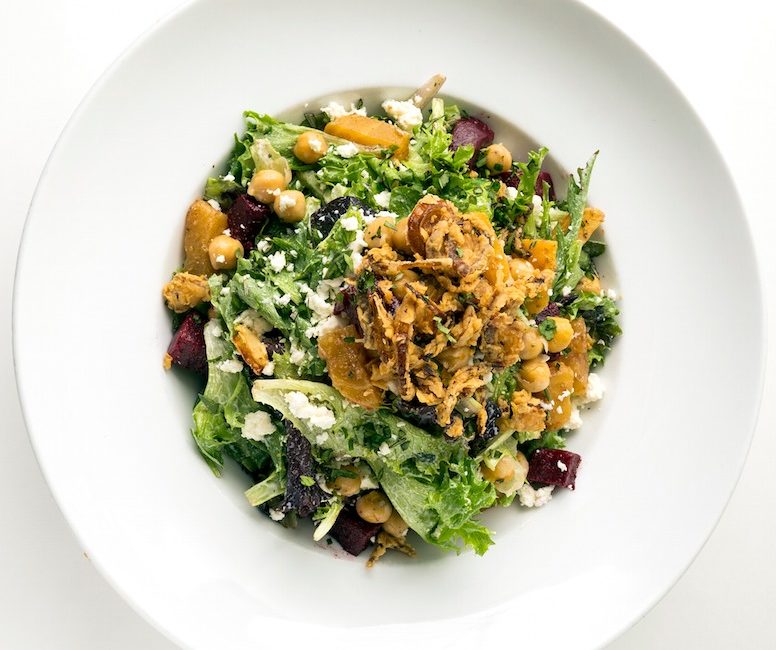 A green salad with fried shallots, red and golden beats, and sheep’s milk feta