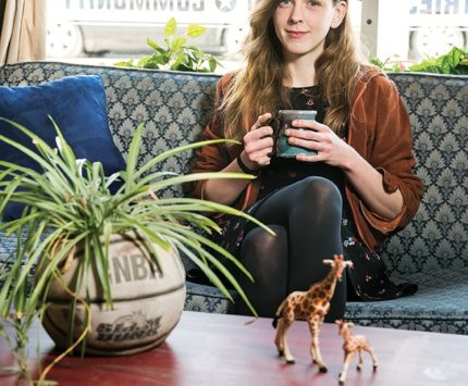 A woman holds a coffee mug while sitting on a couch.