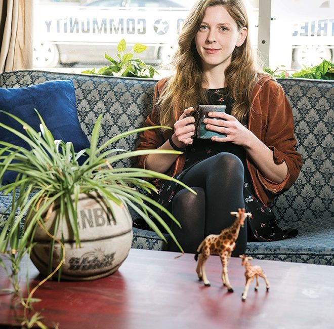 A woman holds a coffee mug while sitting on a couch.