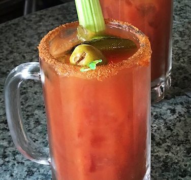 A large mug of Bloody Mary garnished with the requisite celery stalk.