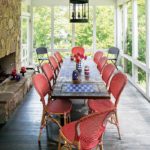 A long, wooden dining table surrounded by red chairs and a fireplace.