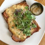 House-cured ham sandwich dressed with crab spread and micro greens.