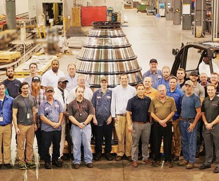 Men stand on a factory floor.