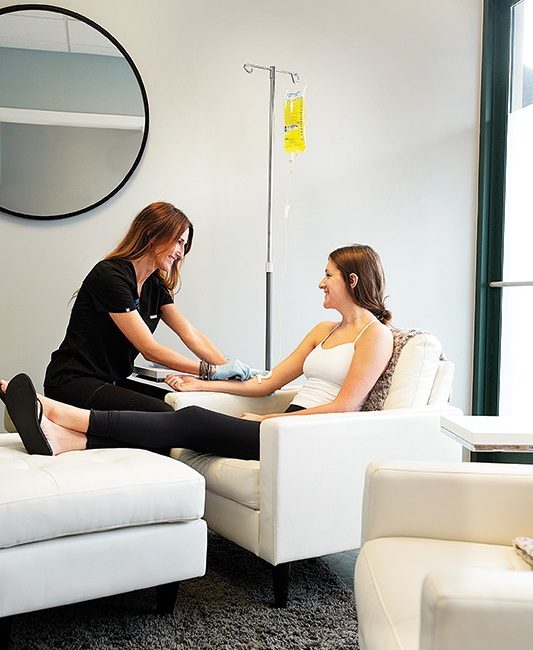 A woman sits reclined in a char while an IV drip is attached to her arm.