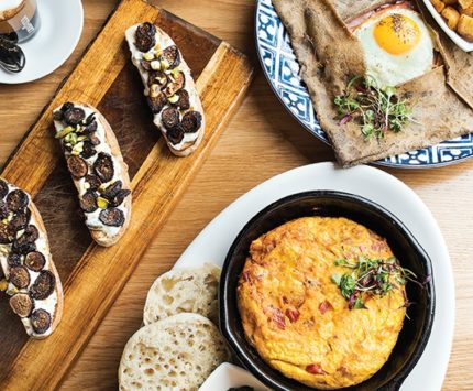 A breakfast setting of eggs, smoked salmon, and roasted vegetables.