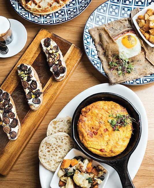 A breakfast setting of eggs, smoked salmon, and roasted vegetables.