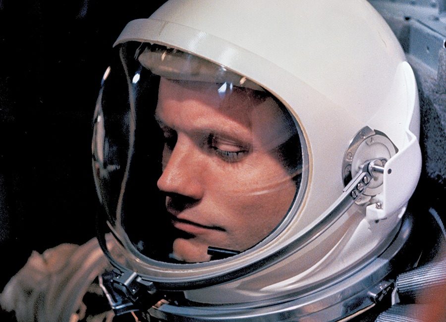 A man sits with a space helmet and suit on.