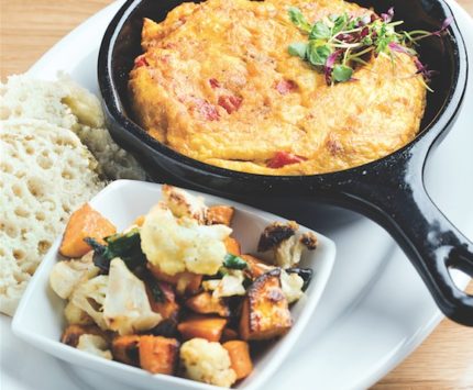 A skillet of eggs with a side of roasted vegetables