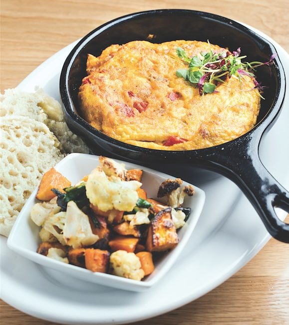 A skillet of eggs with a side of roasted vegetables