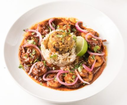 A bowl of a spicy shrimp dish with rice.