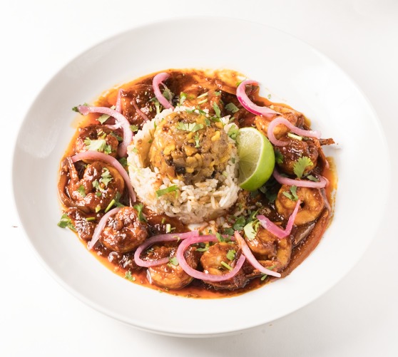 A bowl of a spicy shrimp dish with rice.