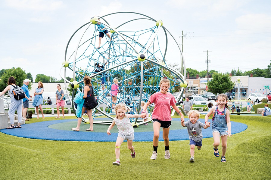 Children run around a playground that features a futuristic climbing orb.