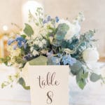 Bokay Florist incorporated shades of soft blue, white, and green into the bouquet and centerpiece