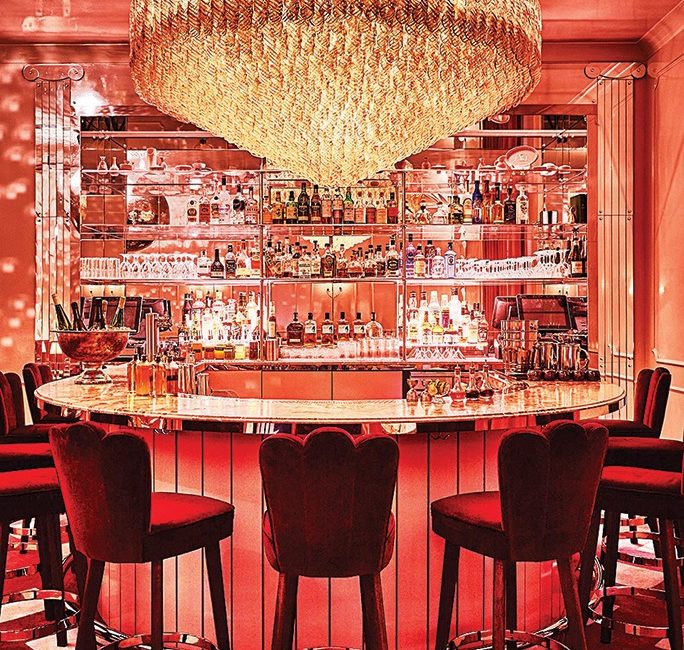 A stylish bar decked out with pink light and a massive chandelier.