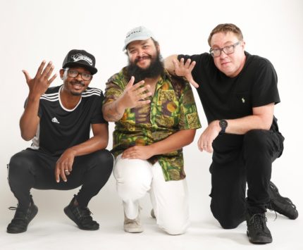 Three guys stand against a white background.