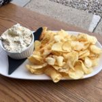 A plate of crispy potato chips with a creamy dip