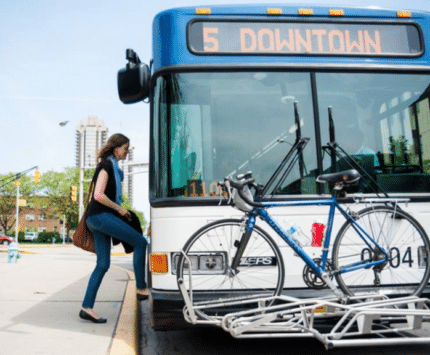 A person boards a city bus from the sidewalk