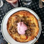 A plate of dutch baby pancake topped with raspberry whipped cream.