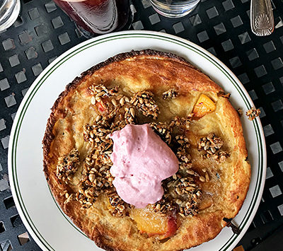 A plate of dutch baby pancake topped with raspberry whipped cream.