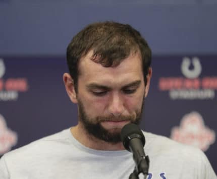 Indianapolis Colts quarterback Andrew Luck stands at a podium announcing his retirement.