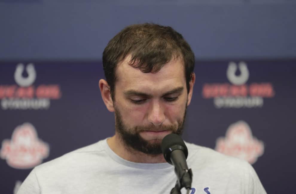 Indianapolis Colts quarterback Andrew Luck stands at a podium announcing his retirement.