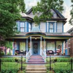 The exterior of a Victorian-era home that is painted in blues, purples, and reds.