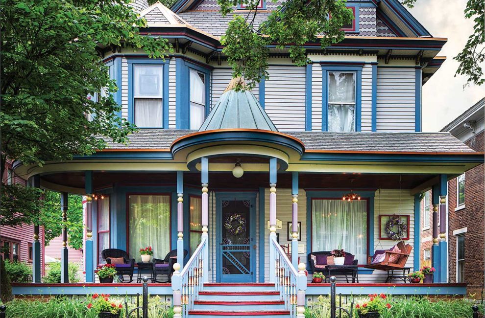 The exterior of a Victorian-era home that is painted in blues, purples, and reds.